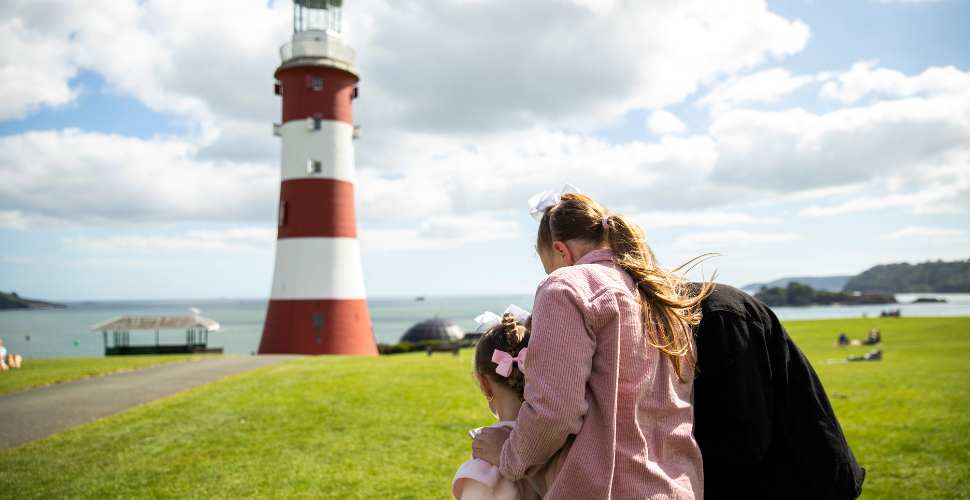 Mother and children using Plymouth Trails app on their iPhone next to Smeaton's Tower